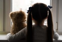 Saúde mental infantil: os efeitos da pandemia ainda estão presentes? criança com ursinho de pelúcia, de costas, parecendo triste, representando a saúde mental infantil