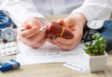 Anticorpos antimitocôndria (AMA): como interpretar na colangite biliar primária médico apontando para fígado com exames e remédios ao redor, ilustrando possível colangite biliar primária e investigação com anticorpos antimitocôndria