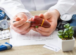 Anticorpos antimitocôndria (AMA): como interpretar na colangite biliar primária médico apontando para fígado com exames e remédios ao redor, ilustrando possível colangite biliar primária e investigação com anticorpos antimitocôndria