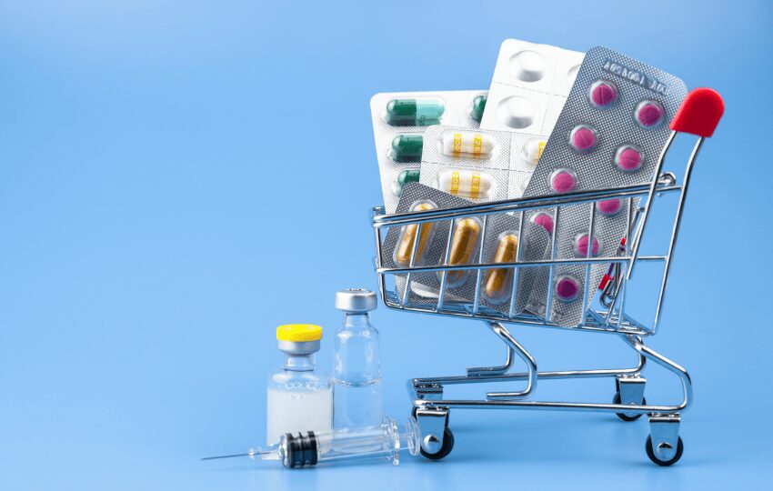 Carrinho de compras em miniatura com comprimidos, ilustrando medicamentos que podem interferir no resultado do exame VHS.