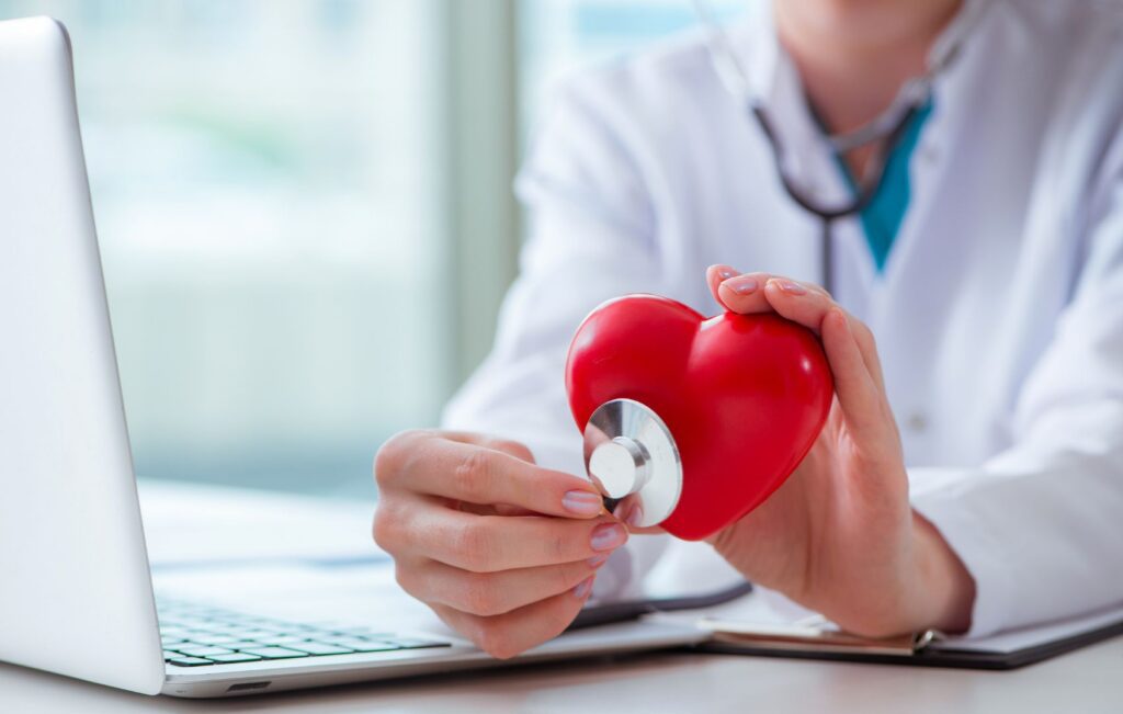 Médico avaliando coraçção (falso) com estetoscópio, representando a avaliação clínica de arritmias cardíacas