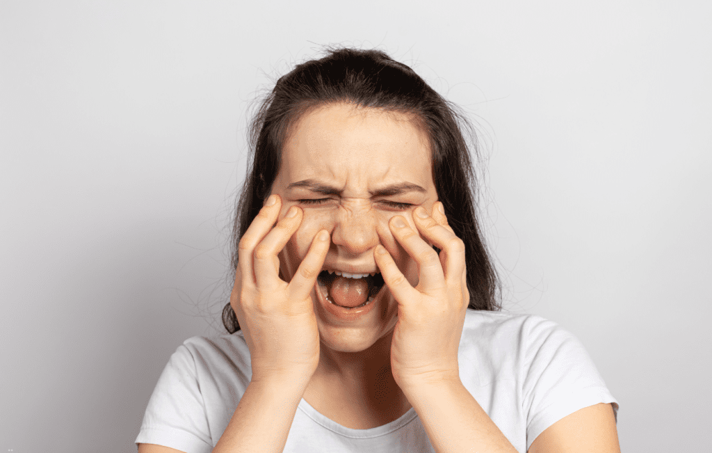 mulher com dor facial intensa, um possível sintoma da neuralgia do trigêmeo