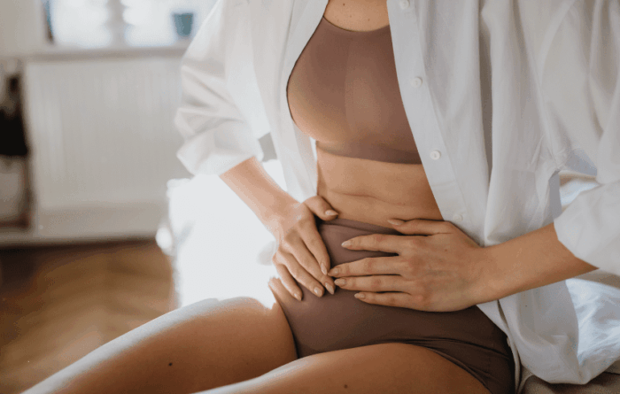mulher segurando a barriga com dor, um dos sinais mais comuns da endometriose