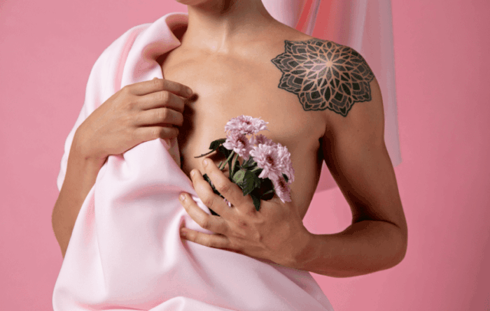 corpo de uma mulher segurando flores na frente do peito, representando paciente com câncer de mama ER+