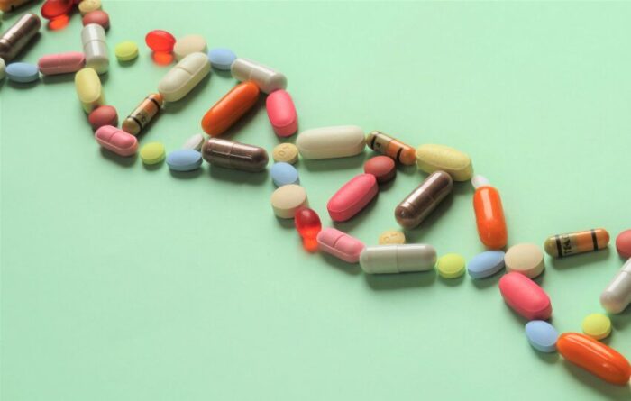 comprimidos e pílulas formando uma hélice de DNA, representando a importância dos estudos de farmacogenética e farmacogenômica