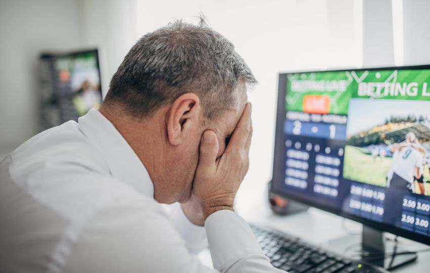 homem em frente a tela de computador parecendo triste por ter perdido um jogo de apostas online