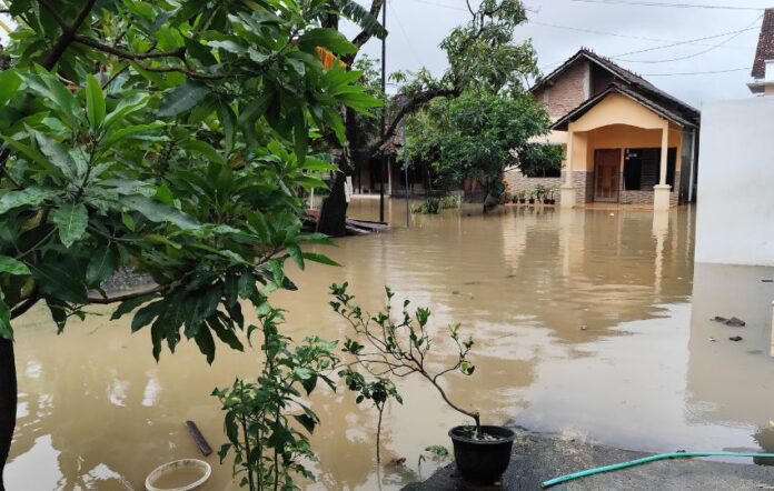 Rua alagada após chuva intensa em área urbana, com risco de doenças transmitidas pela água e leptospirose