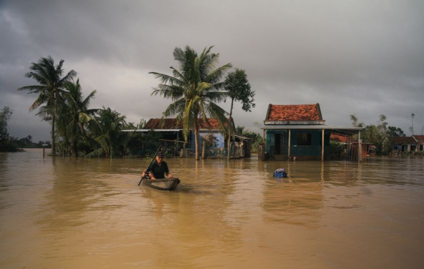 rua alagada com pessoa andando de barco, com risco de doenças transmitidas pela água e leptospirose
