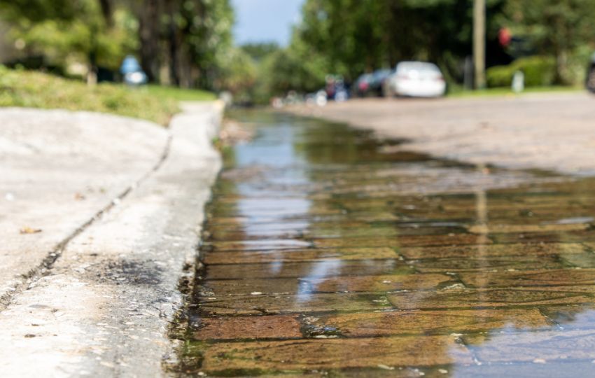 Escoamento de água contaminada após chuva intensa, ilustrando a disseminação de patógenos em doenças transmitidas pela água