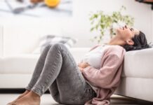 TPM ou TDPM? Entenda a diferença e o que acontece no cérebro na fase lútea mulher sentada no chão, com sinais de irritação e dor abdominal, um possível sintoma de transtorno disfórico pré-menstrual (TDPM)