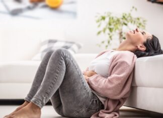 TPM ou TDPM? Entenda a diferença e o que acontece no cérebro na fase lútea mulher sentada no chão, com sinais de irritação e dor abdominal, um possível sintoma de transtorno disfórico pré-menstrual (TDPM)