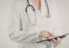 Tratamento da Malária em 2026: novos esquemas, tafenoquina e testagem de G6PD Médico revisando algoritmo de tratamento da malária com recomendações atualizadas sobre tafenoquina e testagem de G6PD.