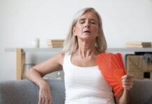 Anvisa aprova fezolinetanto (Veoza): o que muda no tratamento não hormonal da menopausa? mulher se abanando com leque por conta dos sintomas vasomotores da menopausa, que podem ser amenizados com fezolinetanto aprovado pela Anvisa