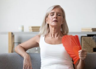 Anvisa aprova fezolinetanto (Veoza): o que muda no tratamento não hormonal da menopausa? mulher se abanando com leque por conta dos sintomas vasomotores da menopausa, que podem ser amenizados com fezolinetanto aprovado pela Anvisa