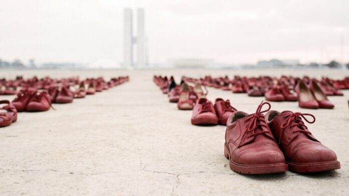 vários sapatos vermelhos alinhados, representando a invisibilidade da violência de gênero e a importância da identificação do feminicídio na CID-11 para a saúde